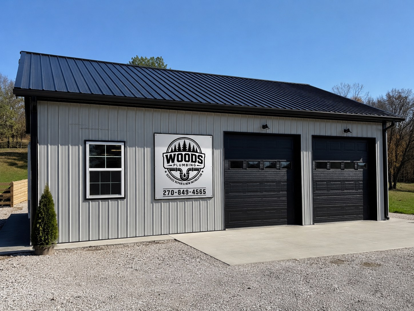 Woods Plumbing company building with sign and black garage doors